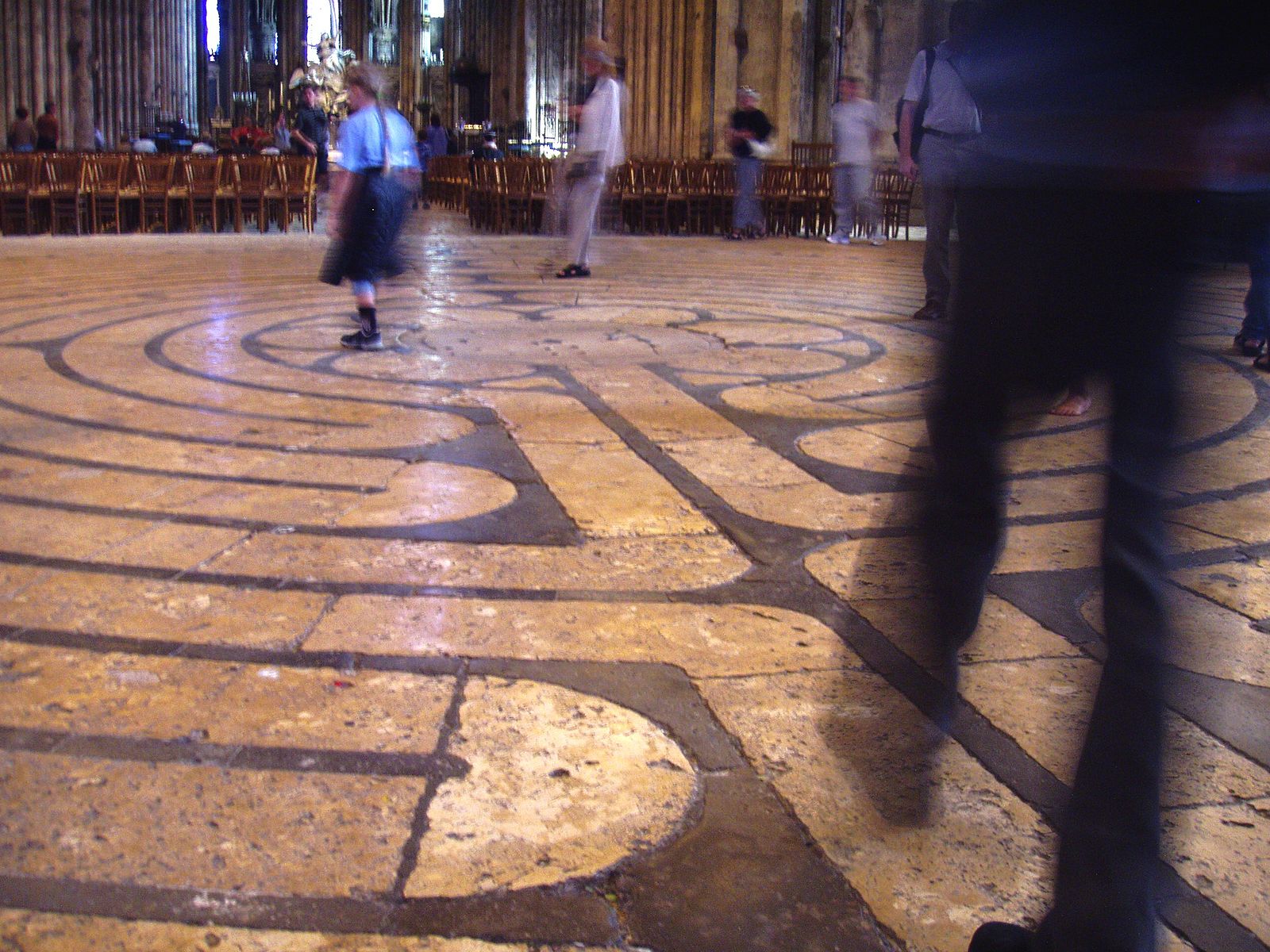 A photograph of visitors in motion walking on the labyrinth design of Chartres Cathedral.