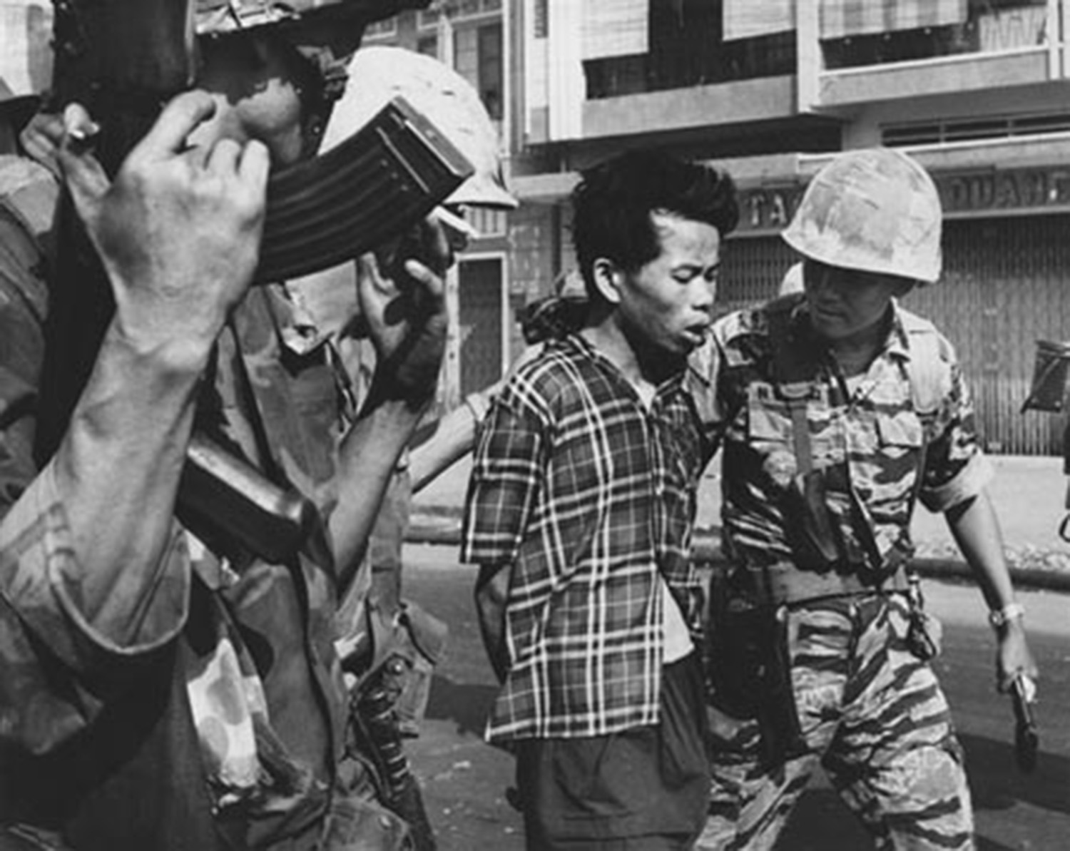 Black and white photograph of a captured Viet Cong officer, Nguyen Van Lem, led by South Vietnamese soldiers, moments before being executed.